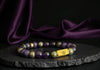 Rengetsu Gyōshin Fire Stillness luxury Charoite men’s bracelet 17 cm displayed on black stone with draped purple satin background – signature piece photoshoot